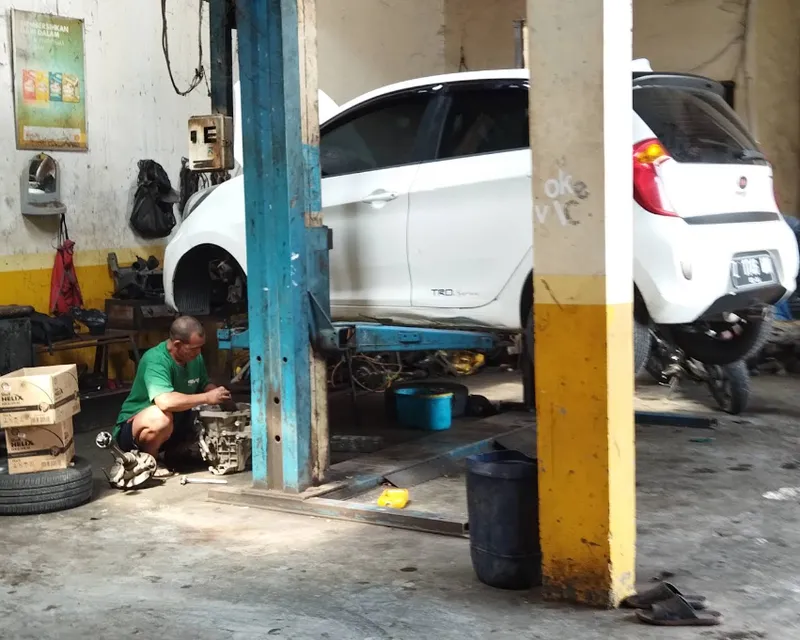 Mekanik Sinar Surya Auto Care mengerjakan mobil di atas lift di area servis